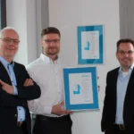 Drei Männer präsentieren stolz das CrefoZert Bonitätszertifikat, das sie im zweiten Jahr in Folge erhalten haben.