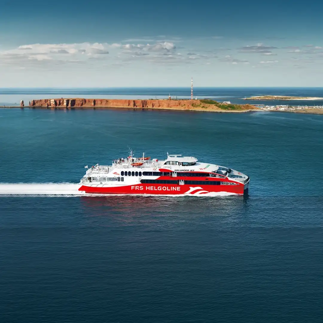 Schnelles Fährschiff der FRS Helgoline auf dem Meer vor der Küste von Helgoland unter blauem Himmel.
