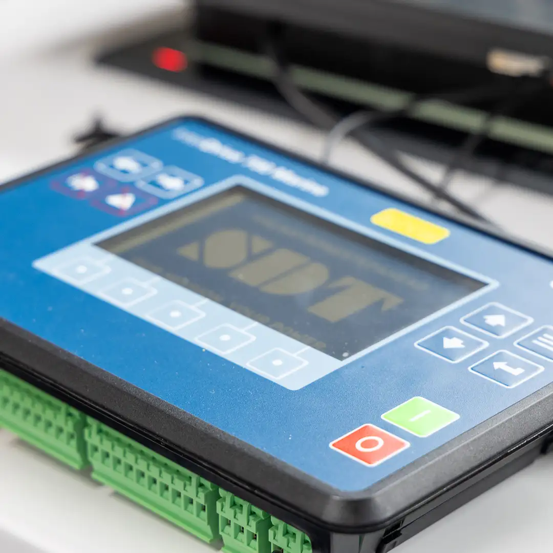 Blaues elektronisches Gerät mit Display und Tasten zur Steuerung, auf einem Tisch platziert.
